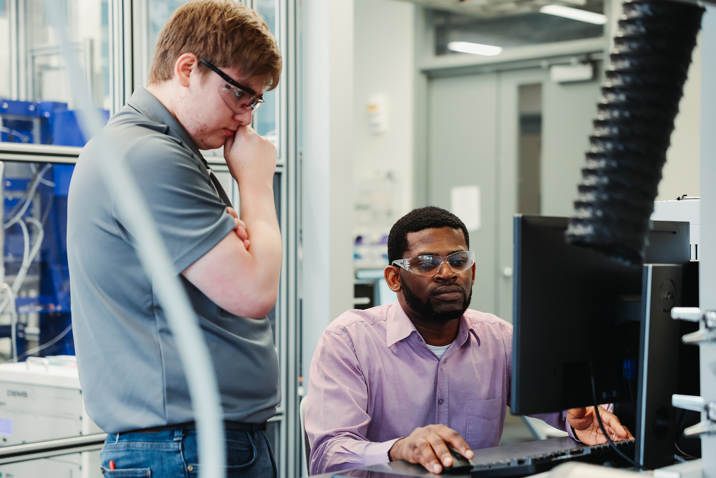 Two researchers look at results on a computer screen