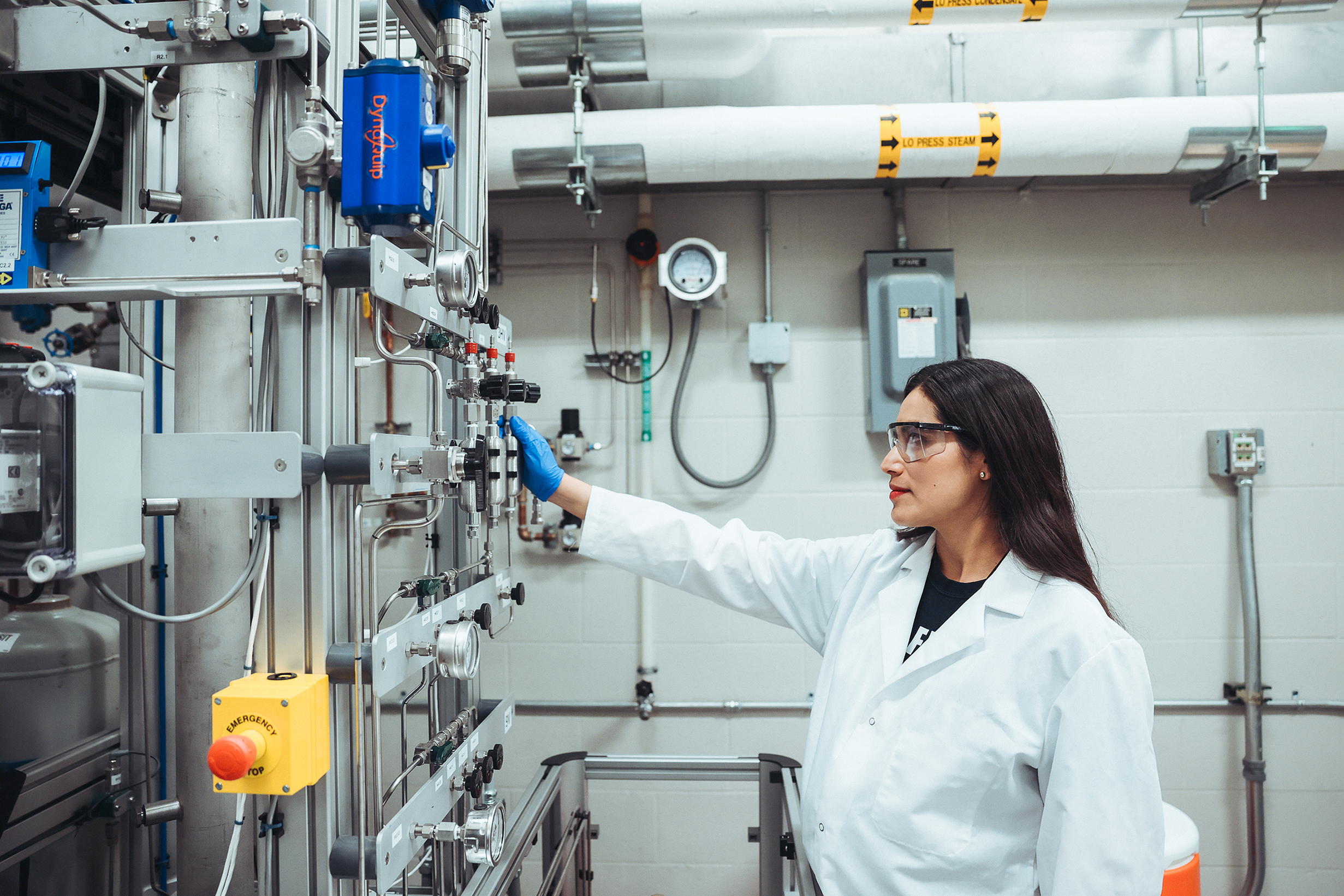 A student in a lab coat looking at some equipment