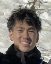 Spencer smiling outside wearing a black jacket.